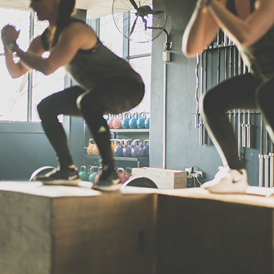 Femmes font du squat sur des box dans une salle de sport