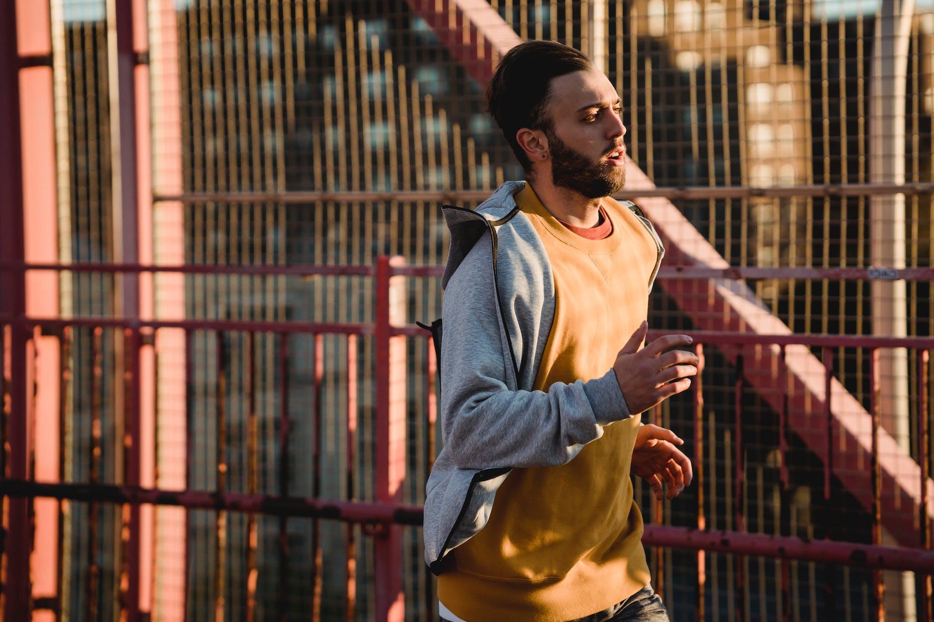 sportif déterminé faisant son jogging sur un pont clôturé en plein soleil