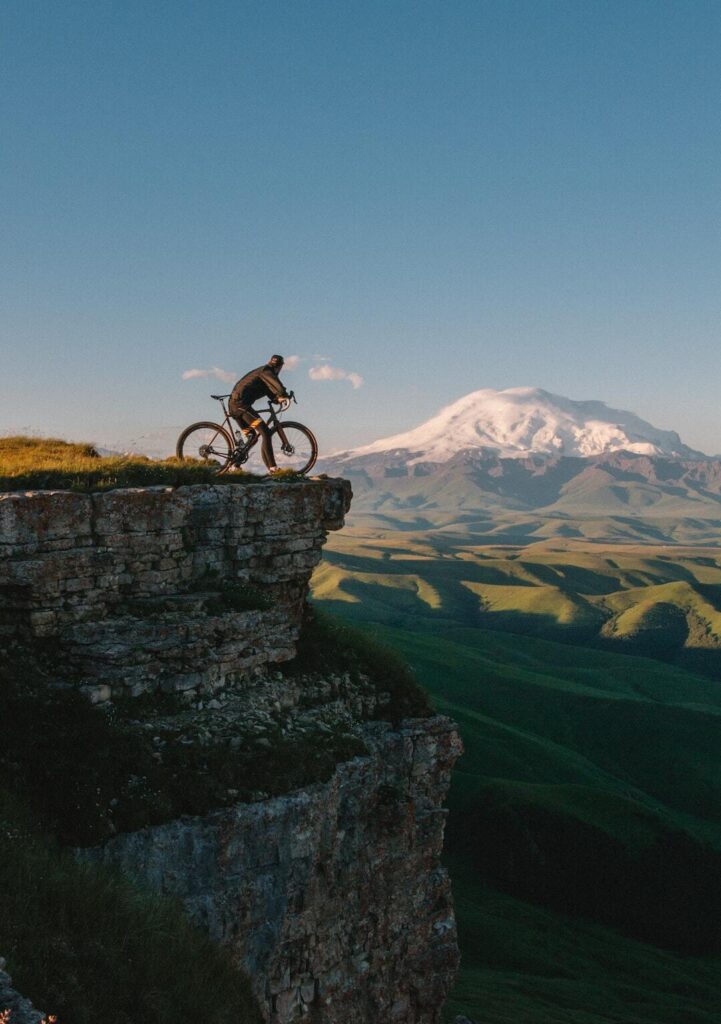 Un homme sur un vélo gravel au bord d'une falaise à la montagne