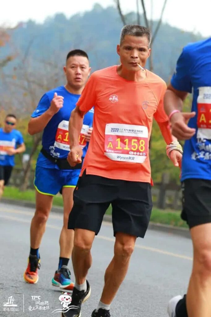 Un coureur chinois fume pendant une compétition de course à pied sur route gros plan
