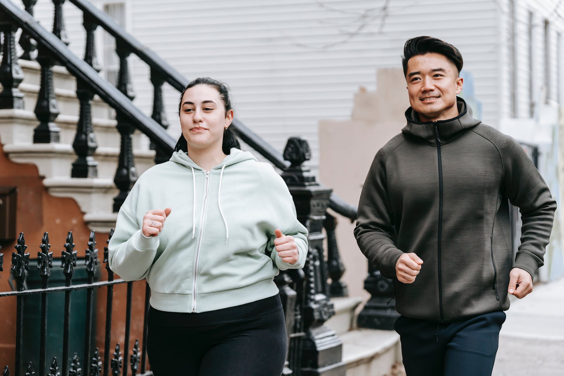 femme de grande taille courant avec un homme asiatique dans la rue en journée