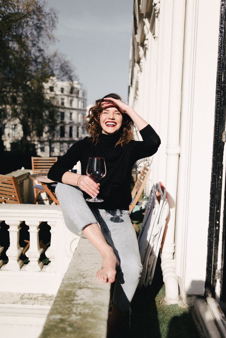 femme heureuse buvant du vin rouge sur un balcon