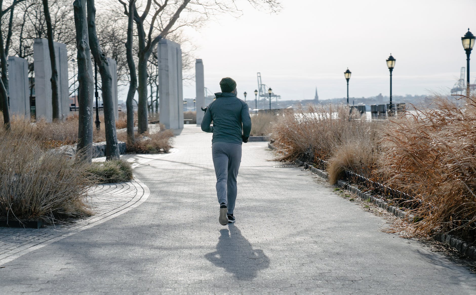 homme en tenue de sport courant sur un sentier dans un parc