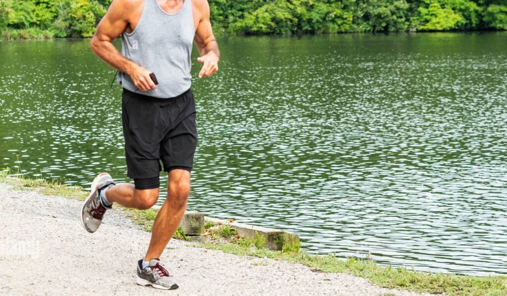 Un coureur est maintenant sur leur téléphone lors de l'exécution d'une course dans les bois, passant d'un lac