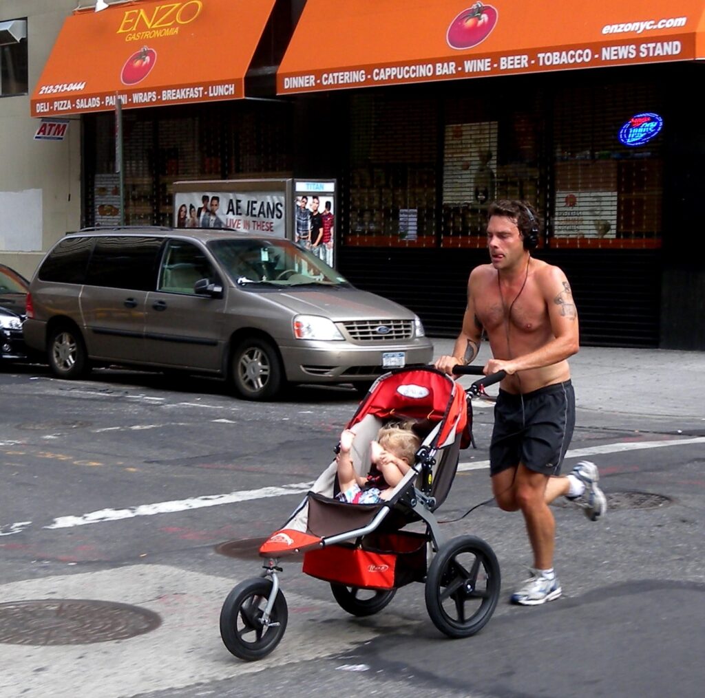 Un homme court avec son enfant dans une poussette dans la rue