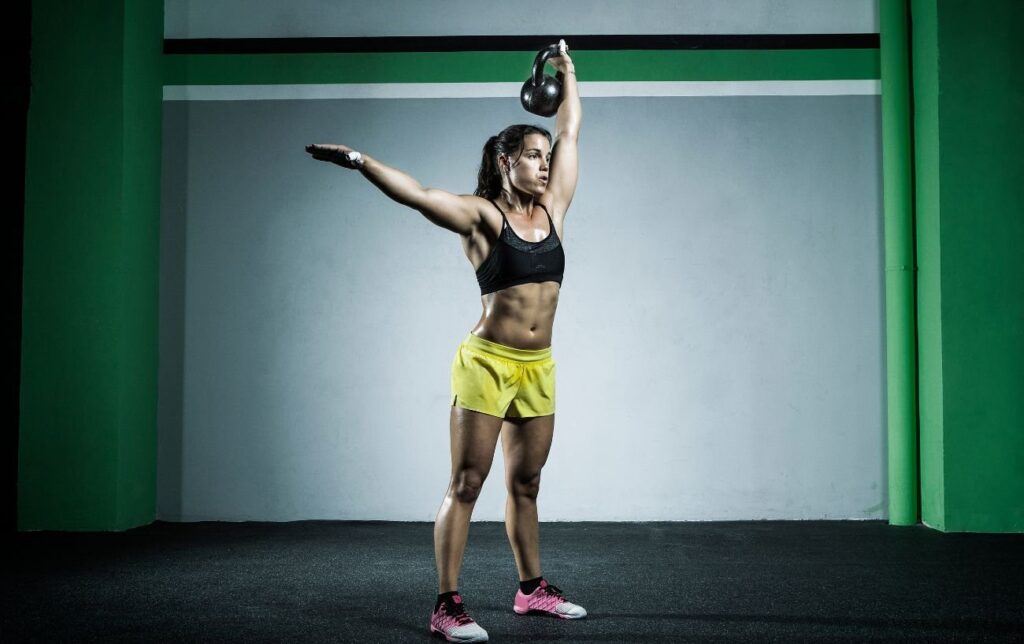 Une femme fait un squat sauté avec une kettlebell