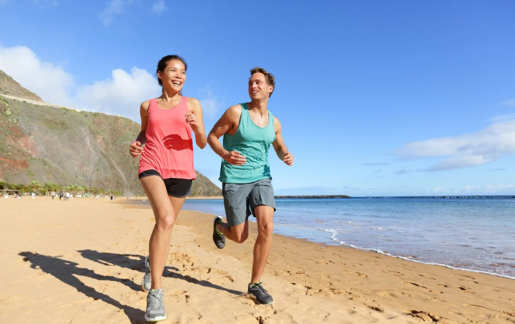 Un couple souriant court sur la plage