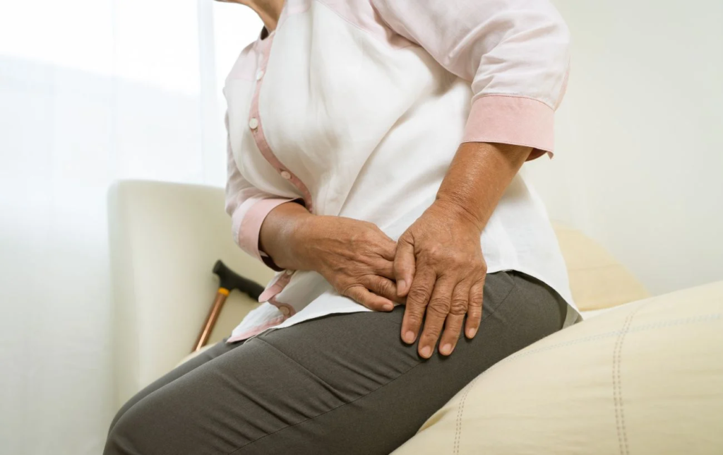 Une femme assise se tient la hanche