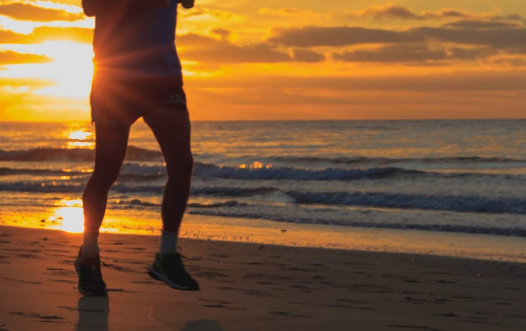 Un homme court sur la plage au coucher du soleil