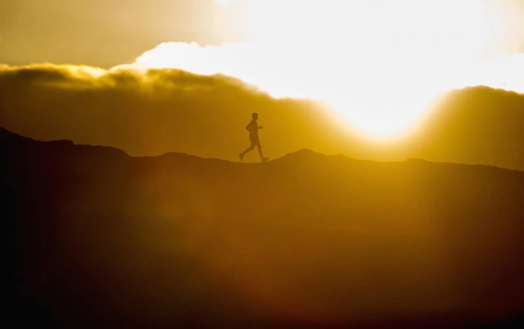 Un homme court en montagne au coucher du soleil
