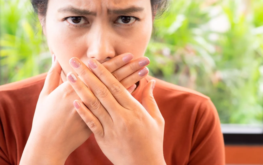 Une femme se tient la bouche avec les mains