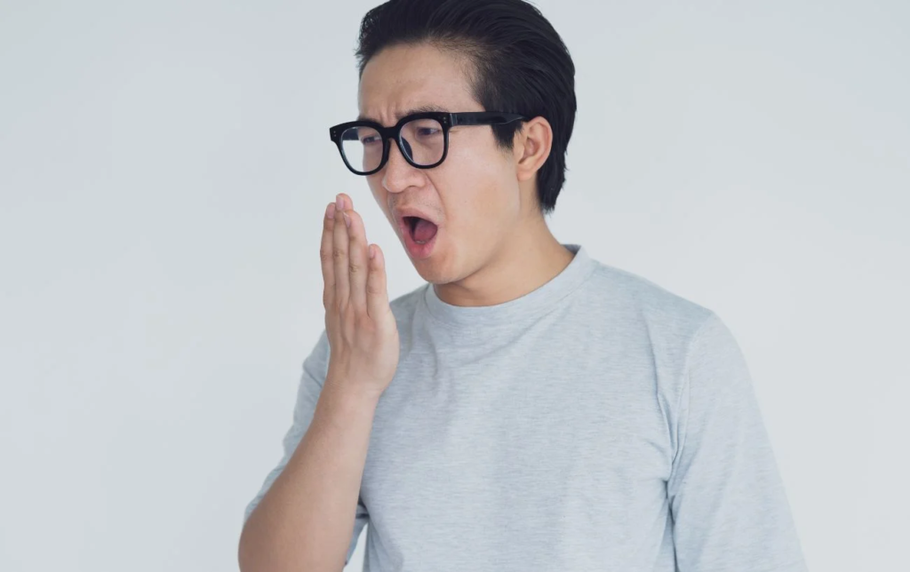 Un homme baille avec sa main