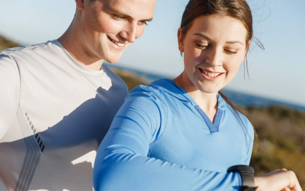 Un couple de coureurs regardent leur montre et sourient