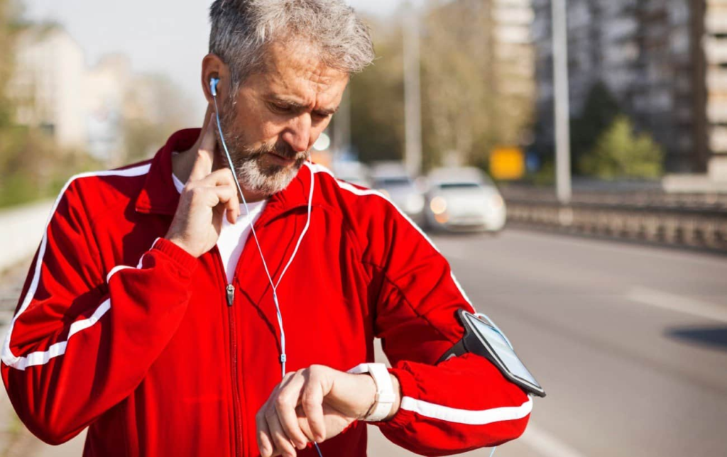 Un homme regarde sa montre GPS et prends son pouls après une séance running