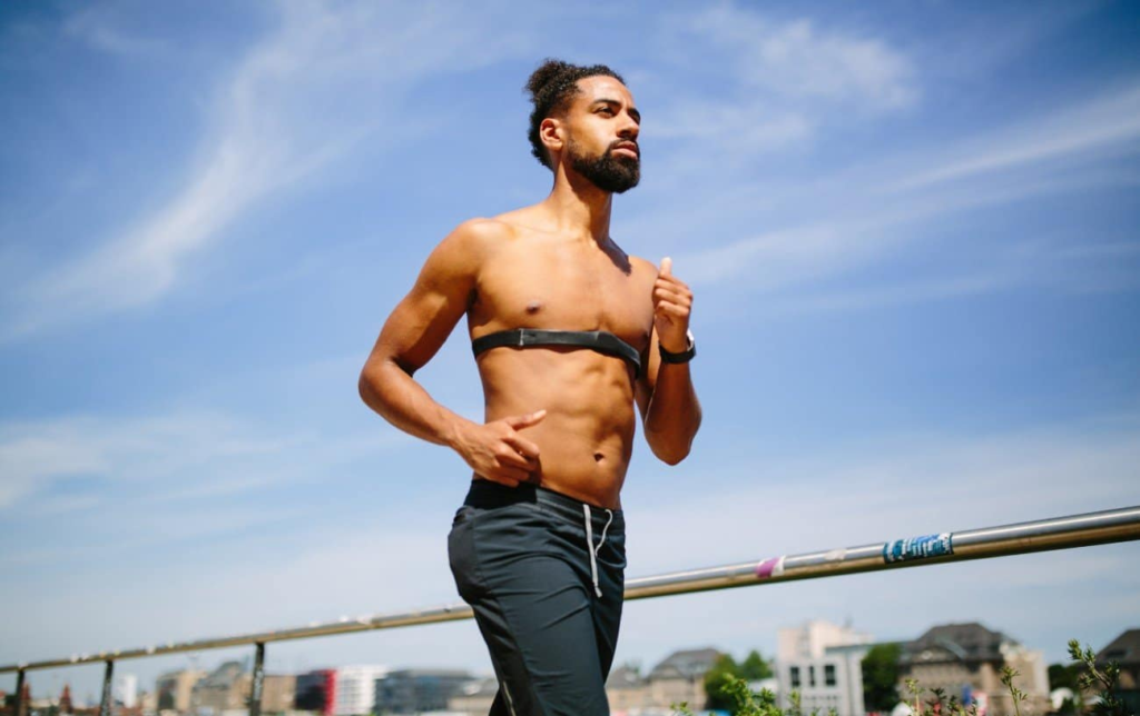 Un homme court torse nu avec une ceinture cardio