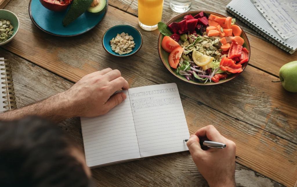 Une personne note des idées de recettes dans un carnet de notes