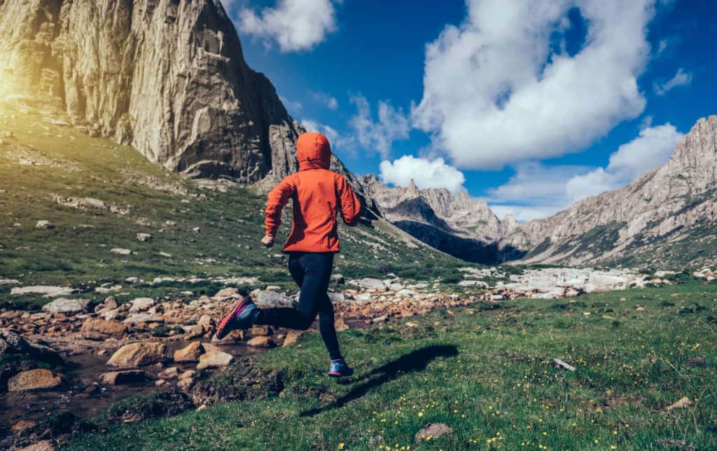 Un homme court dans l'herbe à la montagne