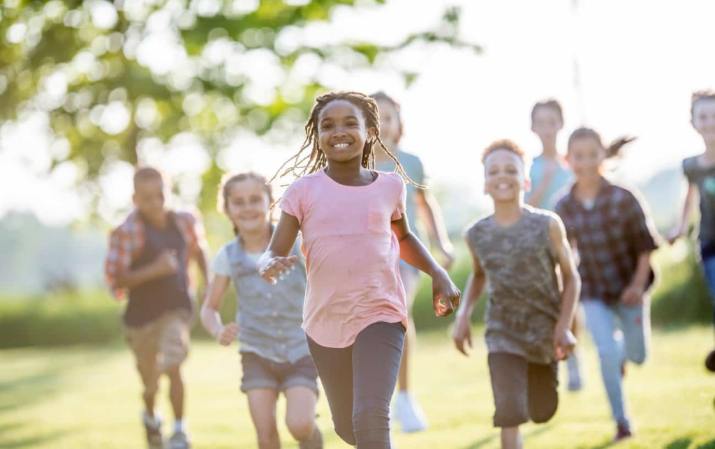 Des enfants en groupe courent sur la pelouse