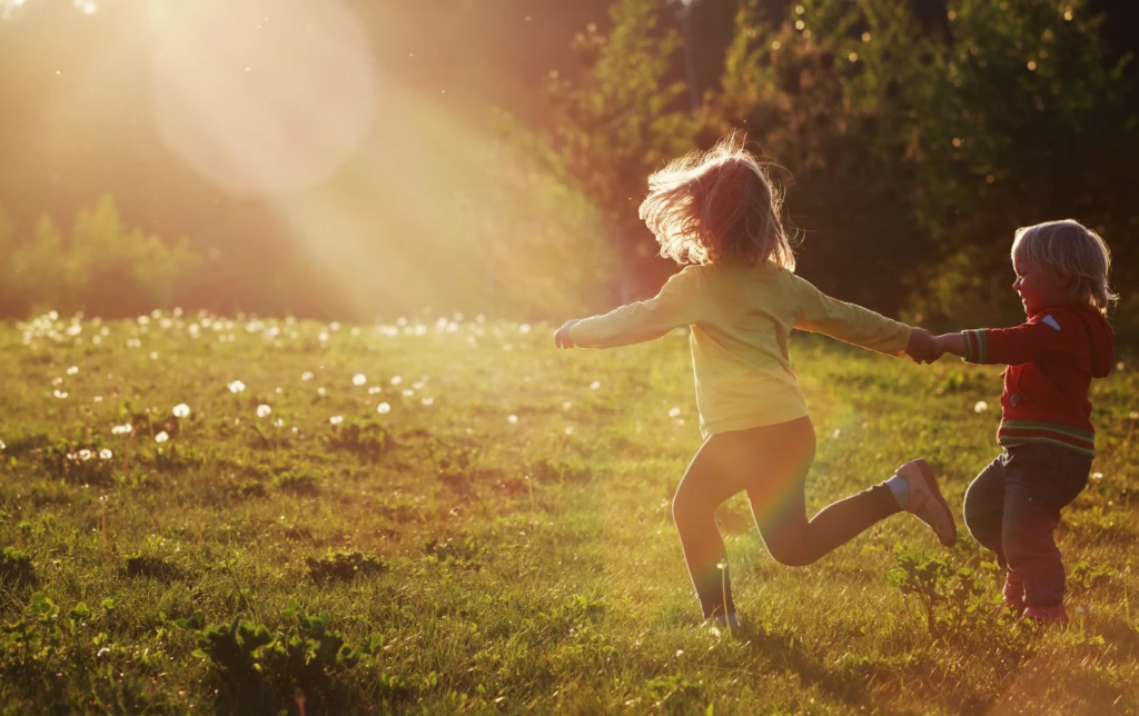 Des enfants courent sur la pelouse et se tiennent la main