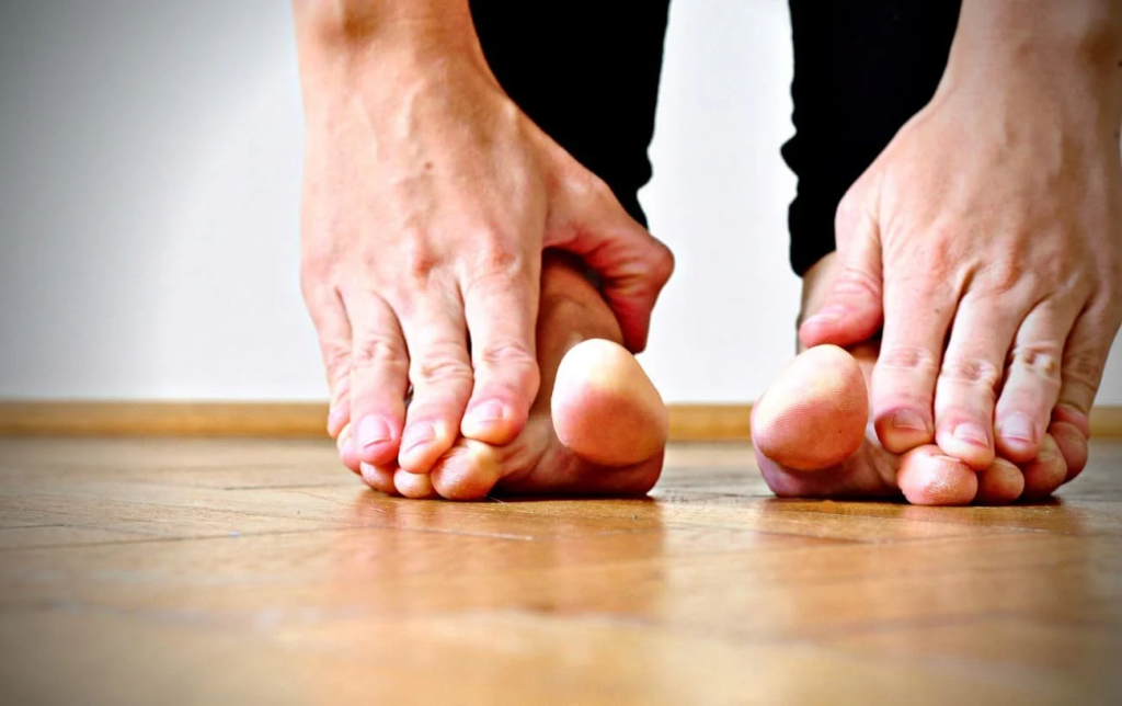Un homme se tient les pieds avec les mains