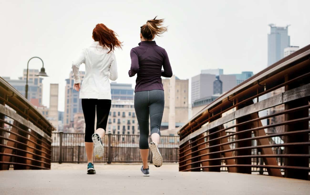 2 femmes courent sur un pont vue de dos