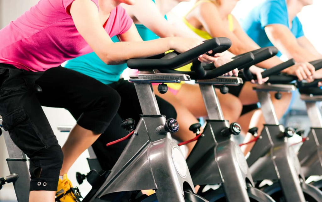 Des femmes pédalent sur des home trainer dans une salle de sport