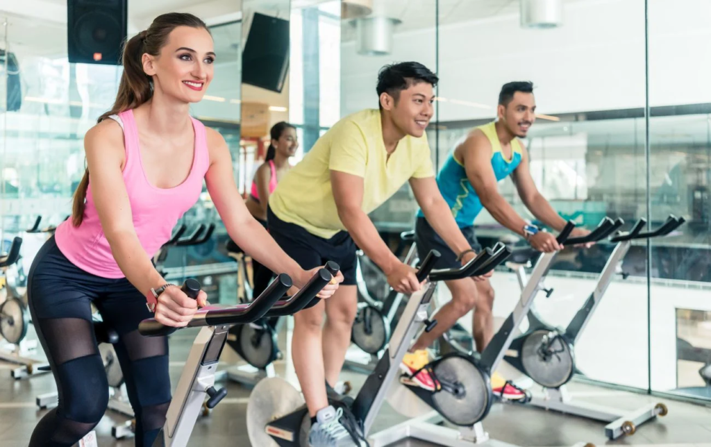 3 personnes font du home-trainer en salle de sport