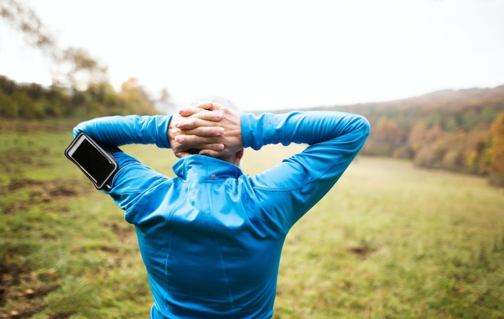Un coureur avec les mains derrière la tête porte un brassard de téléphone au bras