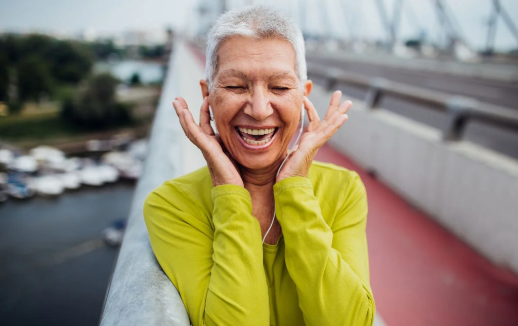 Une coureuse âgée sourit et se bouche les oreilles