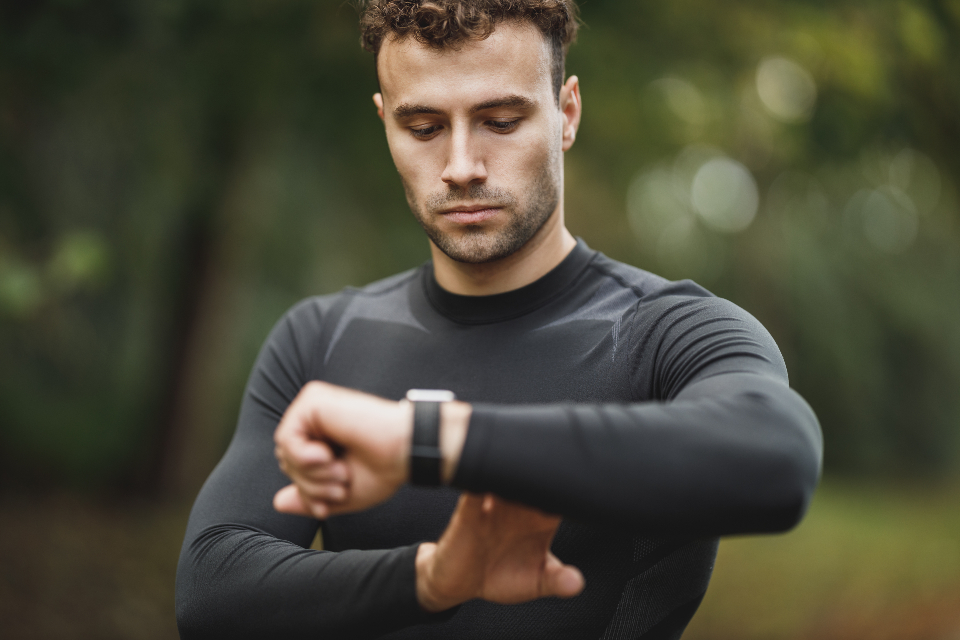 Un coureur immobile regarde sa montre GPS