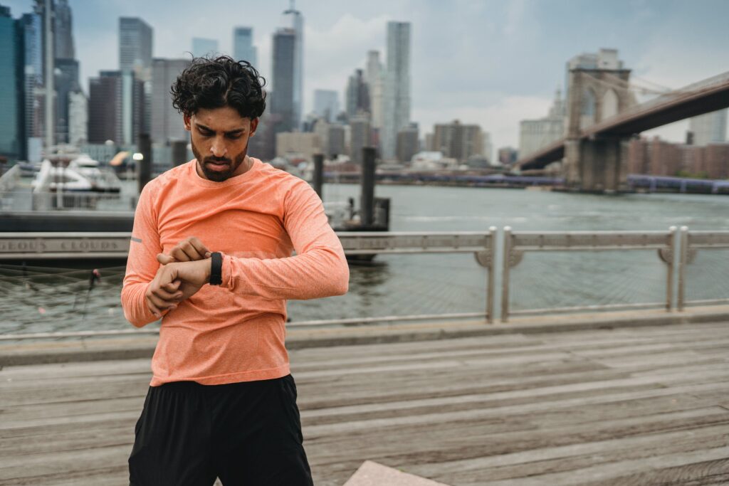 Un coureur immobile regarde et touche sa montre GPS avec la main droite
