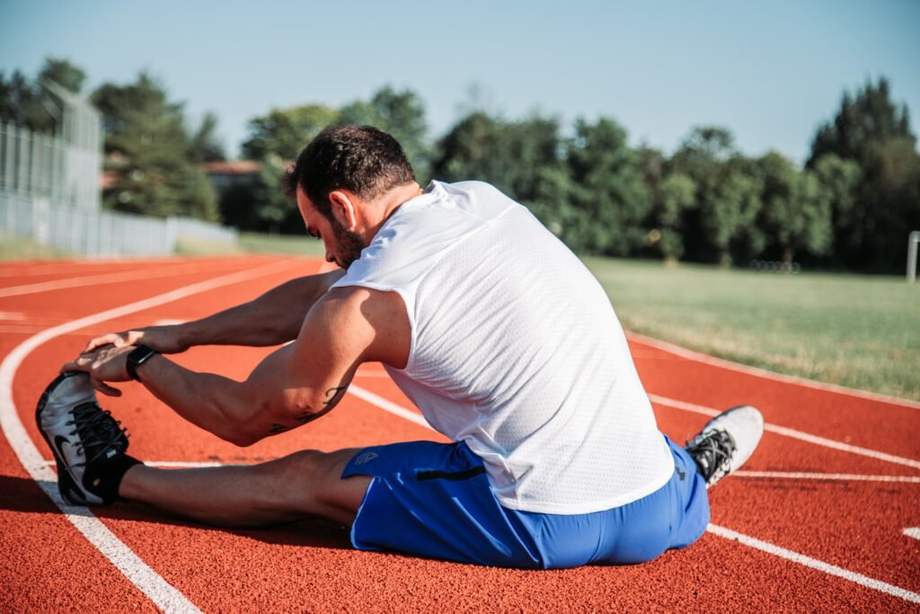 Un coureur s'&eacute;tire le mollet en tirant sur le bout de son pied gauche sur une piste d'athl&eacute;tisme