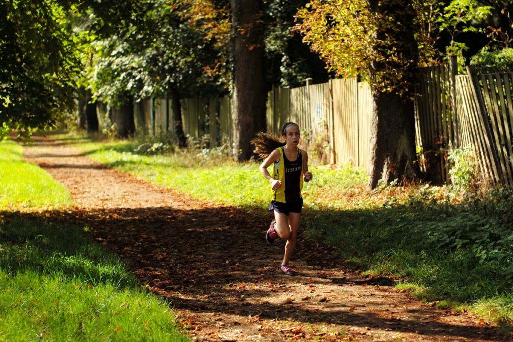 Une fille court sur une route entourée d'arbres
