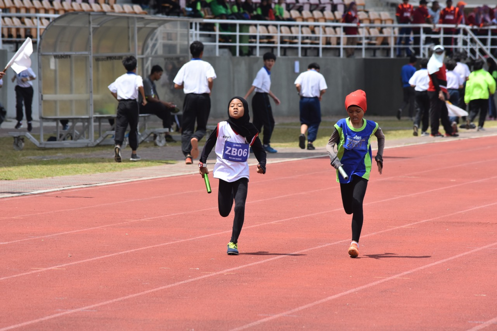 2 filles voil&eacute;es courent sur une piste d'athl&eacute;tisme