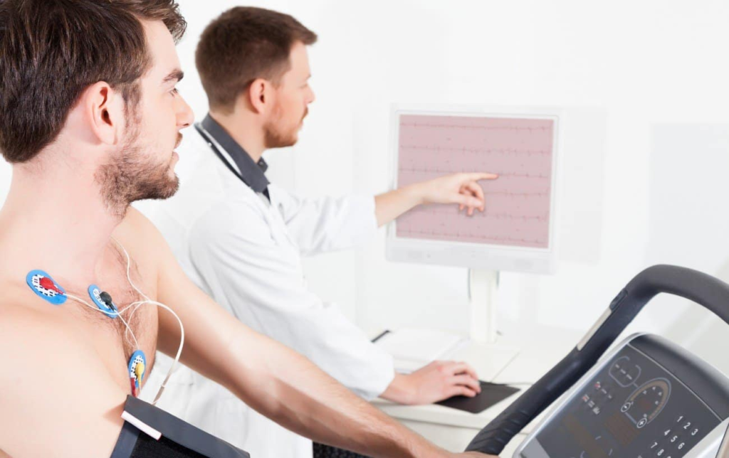 Un patient court sur un tapis de course avec des électrodes sur la poitrine et le docteur lui montre les variations de la fréquence cardiauqe 