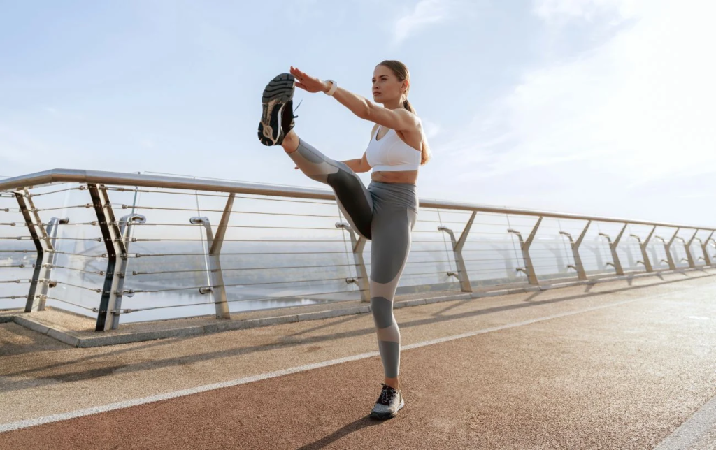 Une femme s'&eacute;chauffe en touchant son pied droit avec la main