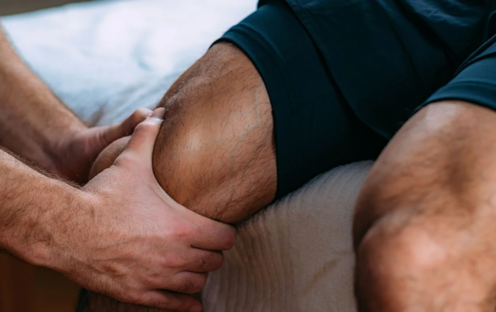 Un sportif se fait masser le genou par un massoth&eacute;rapeute