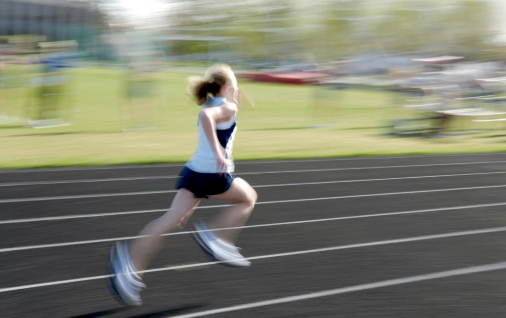 Une jeune femme court sur une piste d'athlétisme