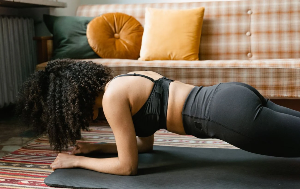 Une femme fait la planche sur un tapis dans son salon
