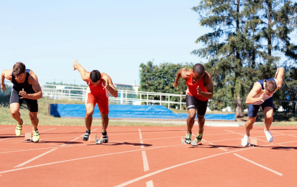 4 coureurs au départ d'un 100 mètres sur une piste d'athlétisme