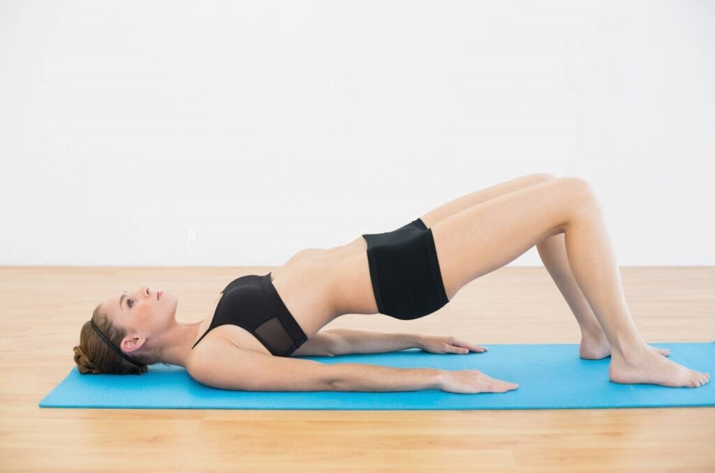 Une femme fait l'exercice de Kegel sur un tapis de gym dans une salle de sport