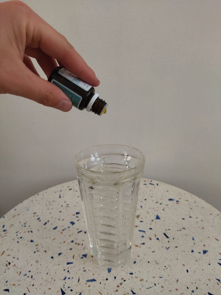 Flacon vitamine D3 UNAE versée dans un verre d'eau