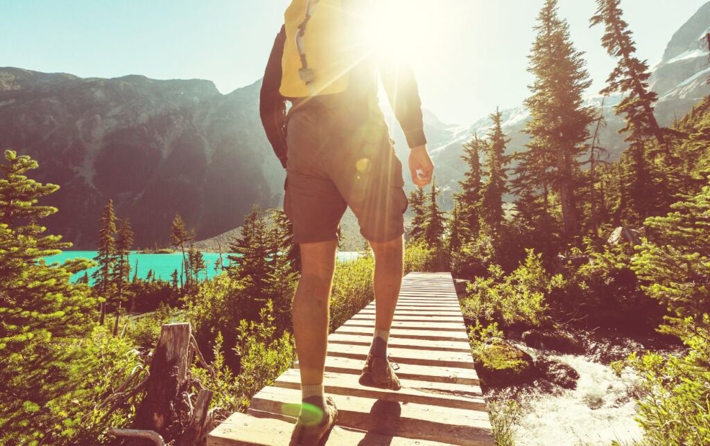 Un homme vue de dos sur un pont fait de la randonnée à la montagne