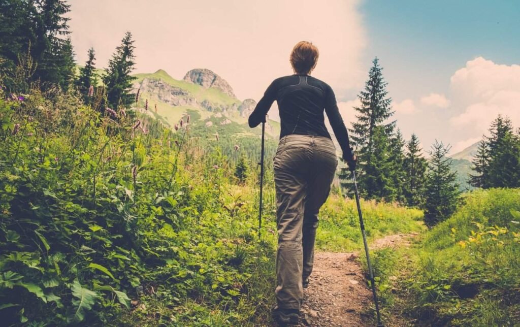 Une femme avec des bâtons de trail sur un sentier de montagne