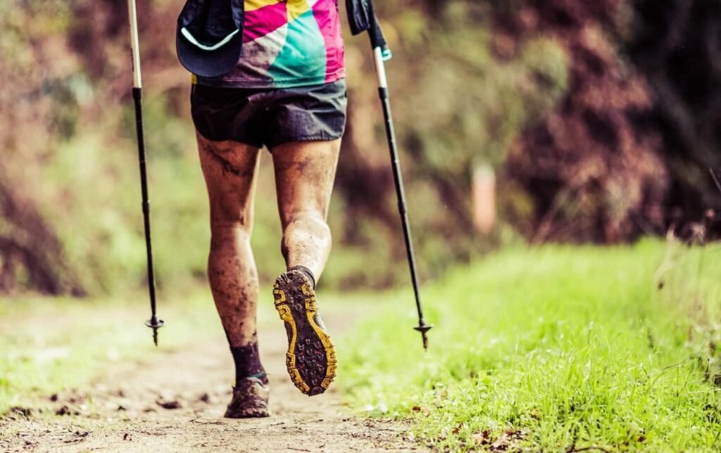 Un traileur avec des bâtons de trail vue de dos sur un sentier